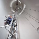 Photo d'un stagiaire de WindLab sur une échelle pendant la maintenance d'une éolienne